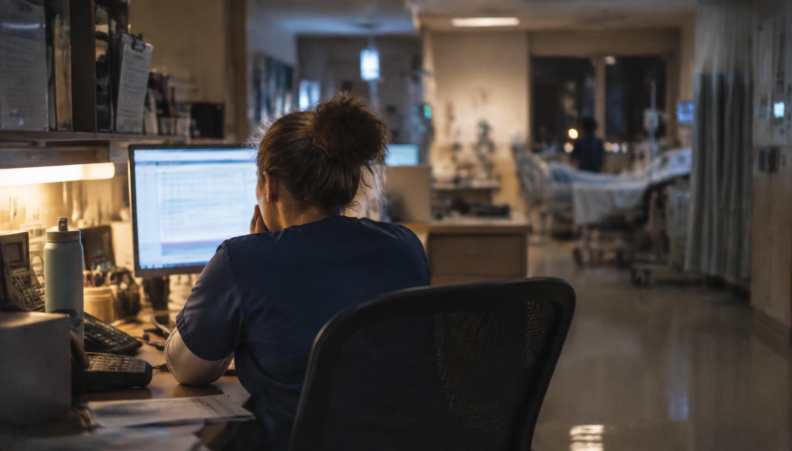 Care coordinator reviewing a patient list at a hospital workstation during a night shift